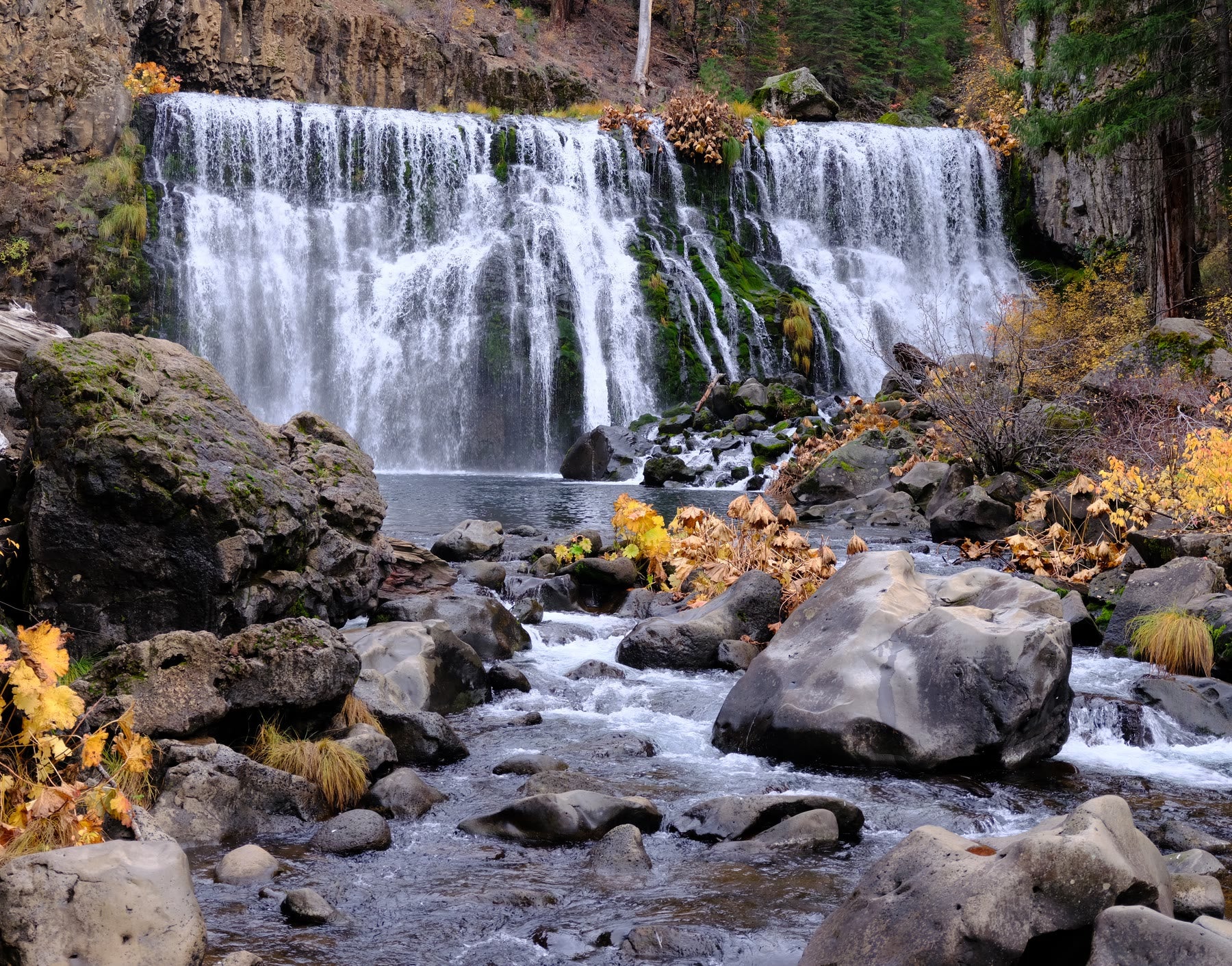Fresh spring water flowing over rocks beneath a waterfall